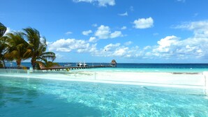 A clear blue sky, a sandy beach, and a pool area with a view of the ocean and a pier. - Exclusive & Safe Location: Turquoise Sea w/ White Sand Beach NO SEAWEED (Cancún)