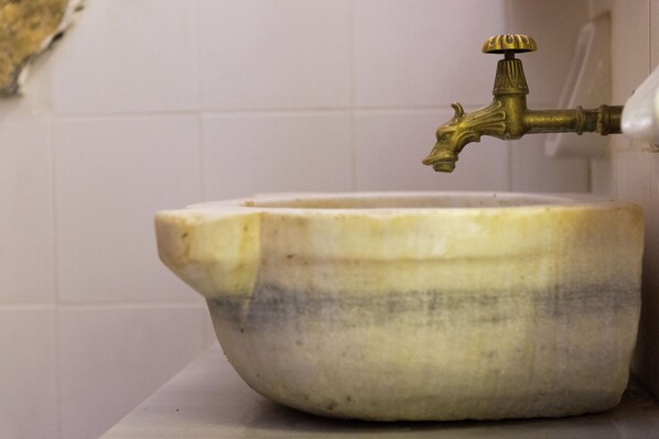 Un lavabo da bagno con un rubinetto d'epoca e una vasca ampia e poco profonda.