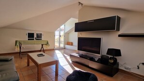 Un salon avec un canapé, une petite table, un téléviseur et une lampe.