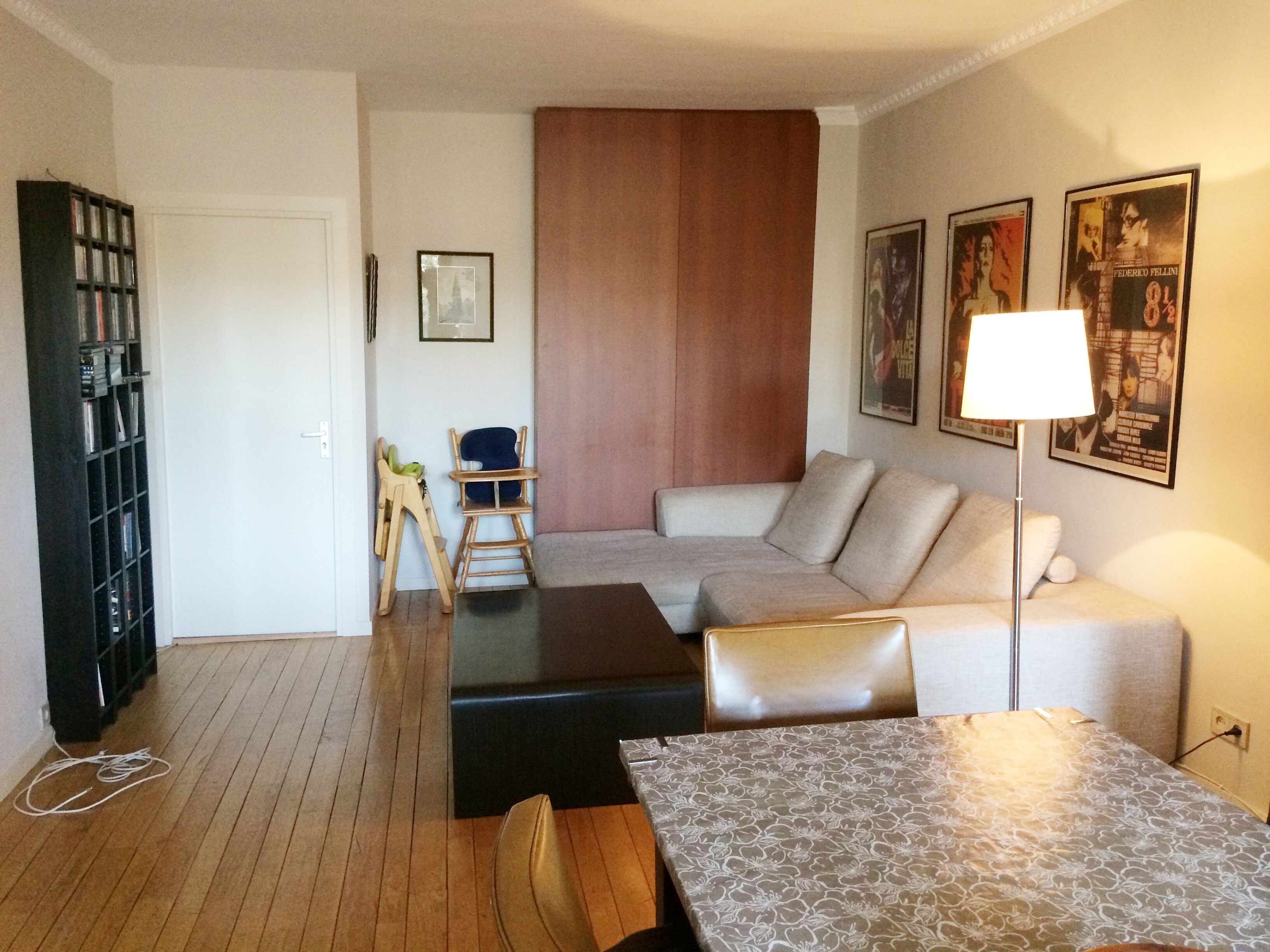 Una sala de estar con un sofá, una mesa de centro, una estantería y una lámpara.
