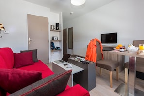 Ein modernes Wohnzimmer mit einem roten Sofa, einem kleinen Couchtisch und einem Laptop.