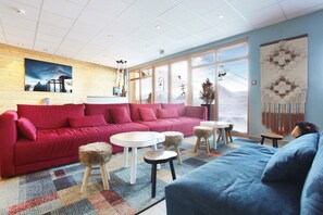 A modern living room with a red sofa, a blue sofa, and a small round table.