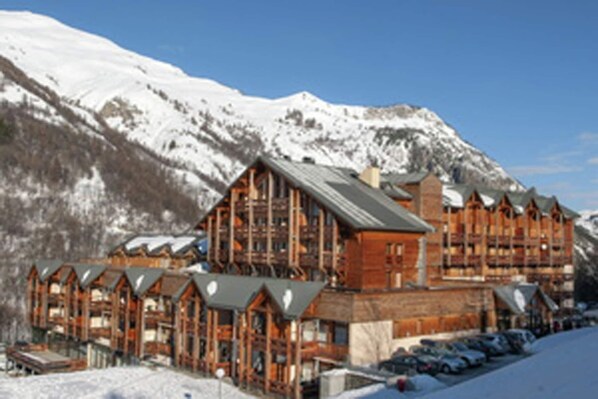 Un chalet avec une façade en bois, de nombreux balcons et une vue sur des montagnes enneigées.