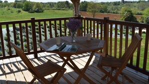 A wooden deck with a table and two chairs, overlooking a river and green fields. - Le Domaine des Ravels, 4-star charm and comfort, calm and relaxation in the countryside (Cause-De-Clérans)
