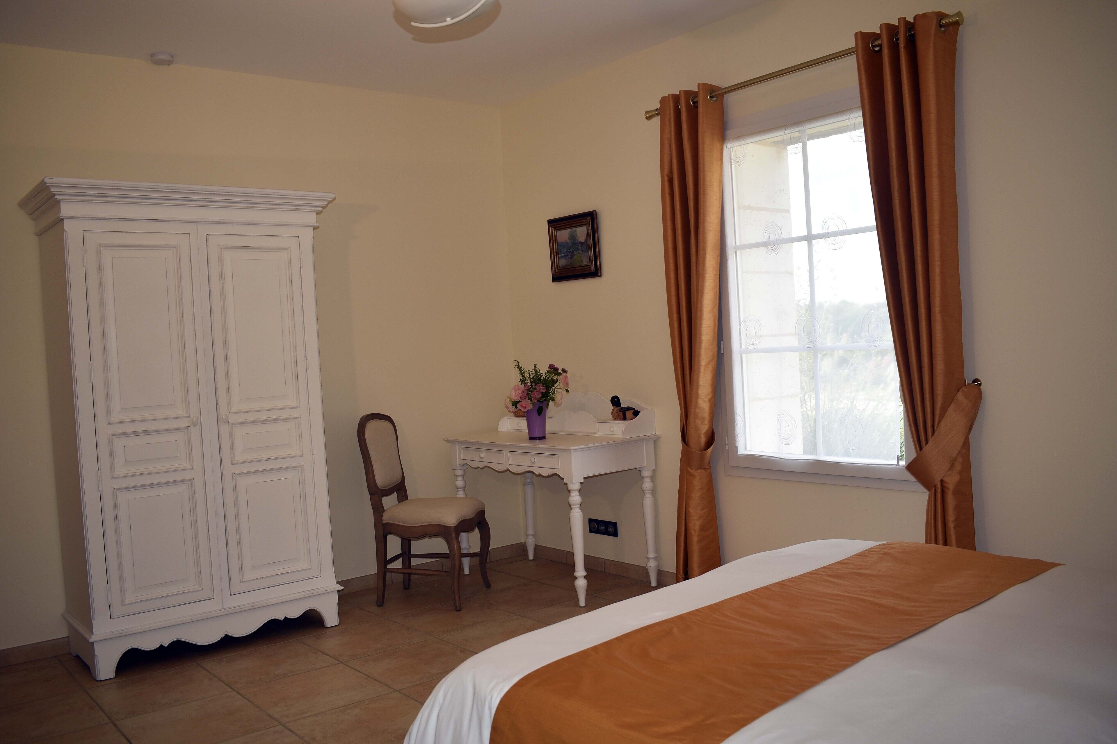 A bedroom with a bed, a desk, a chair, and a wardrobe.