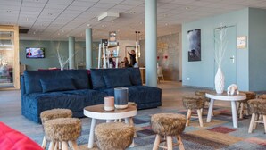 Ein stilvoller Lounge-Bereich mit einem blauen Sofa, runden Tischen und Hockern.