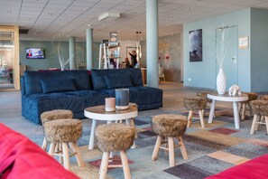 Ein stilvoller Lounge-Bereich mit einem blauen Sofa, runden Tischen und Hockern.