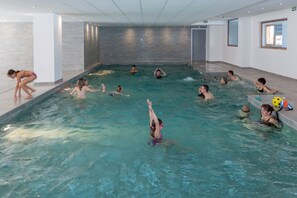 Ein Hallenbad mit mehreren Bahnen, gefliesten Wänden und einer Decke mit Einbaustrahlern.