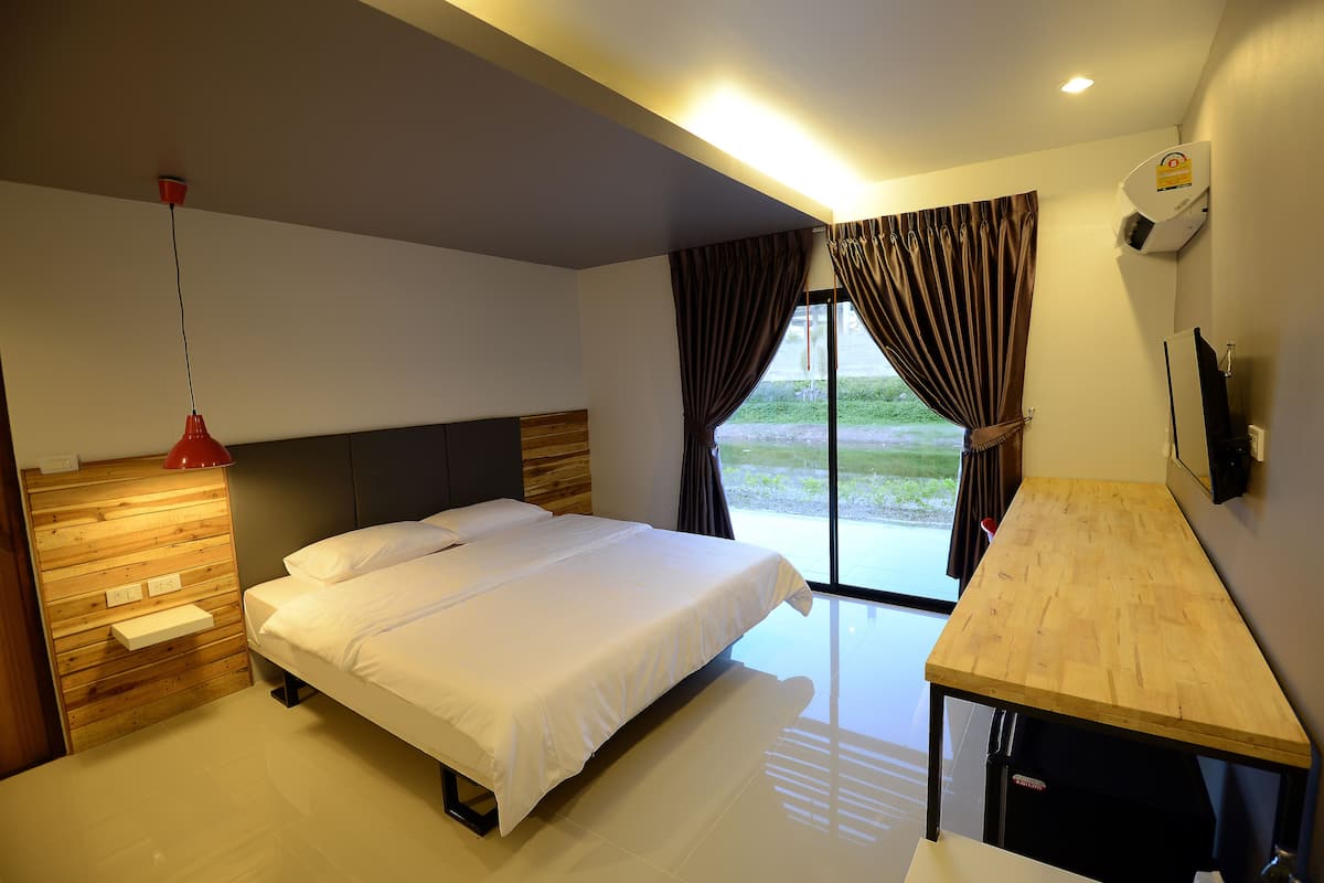 Une chambre d’hôtel moderne avec une tête de lit en bois, un grand lit, une table en bois et une vue sur l’extérieur par la fenêtre.