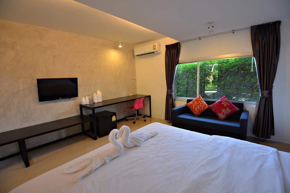 Une chambre d’hôtel avec un lit, un bureau, une chaise, une télévision et une fenêtre avec des rideaux.