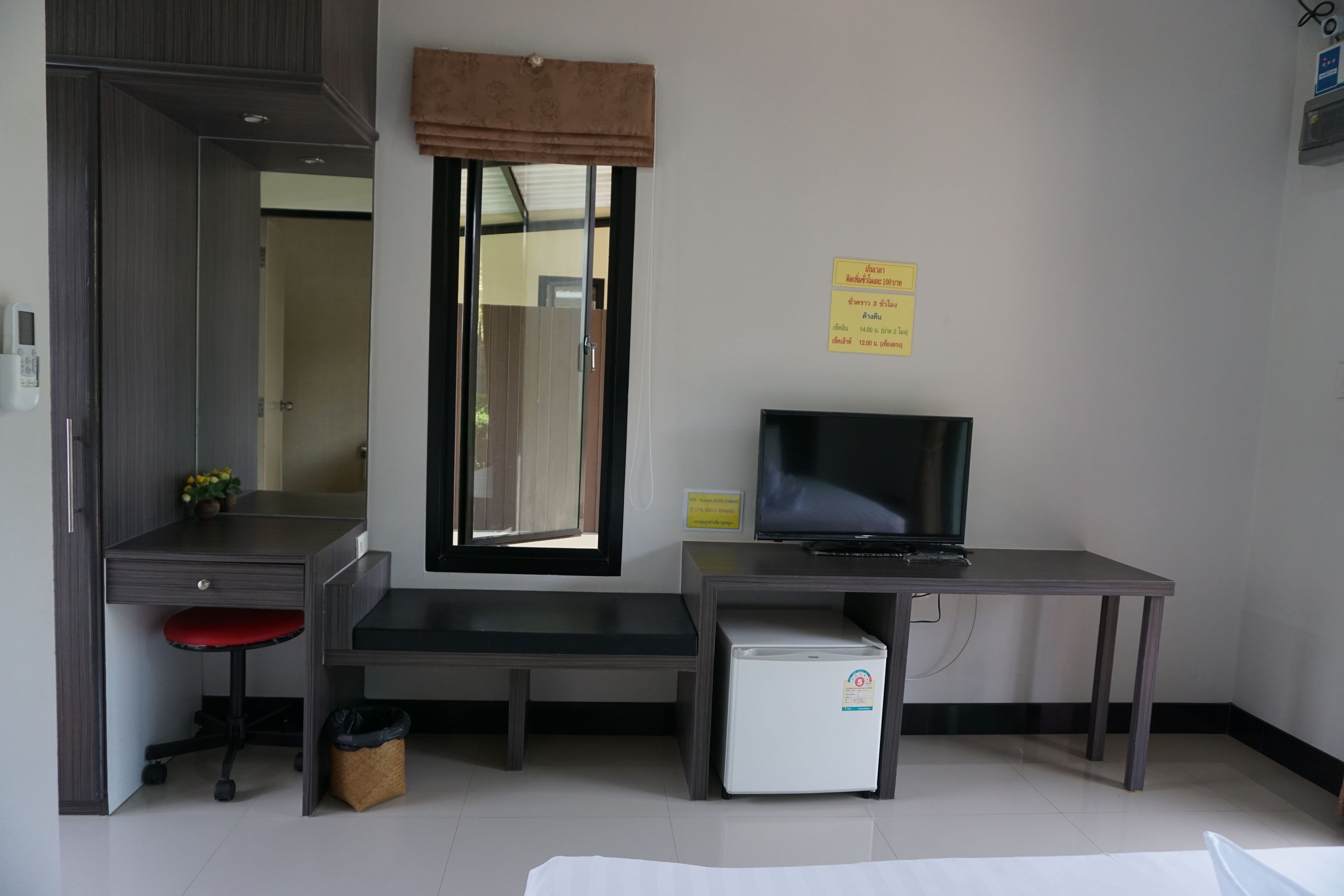 Ein Hotelzimmer mit Schreibtisch, Stuhl, Fernseher und kleinem Kühlschrank.
