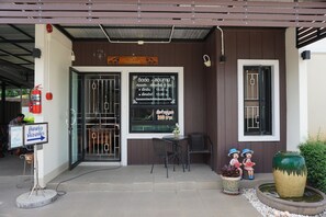 A restaurant entrance with a signboard, a fire extinguisher, a small table with chairs, and a decorative vase. - Phumipat Resort Thungsong (Thung Song)
