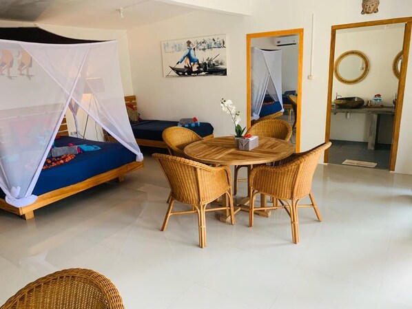 Una habitación con una cama, una mesa de comedor con sillas, un espejo y un cuadro en la pared.