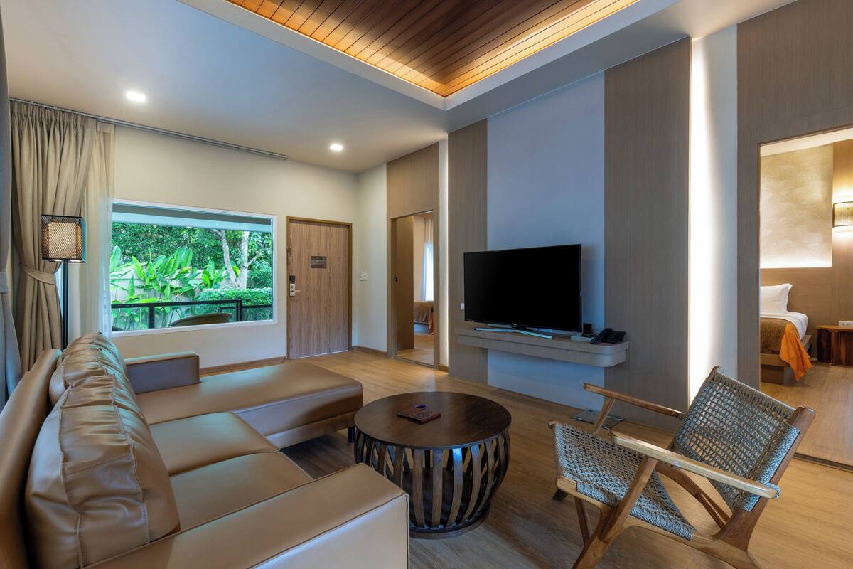 A modern living room with a sofa, a TV, and a wicker chair.