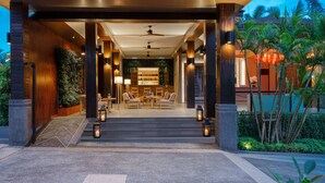 Un moderno vestíbulo de hotel con una zona de estar, un bar y una escalera que sube a los pisos superiores.