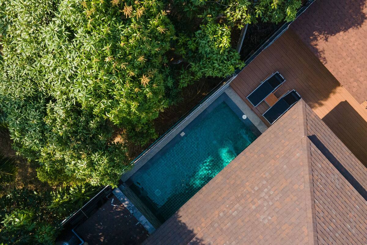 An aerial view of a swimming pool surrounded by lush greenery and a brick structure.