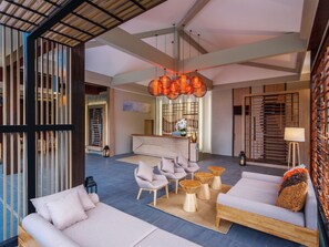 A spacious lobby with a reception desk, seating area, and decorative lighting.