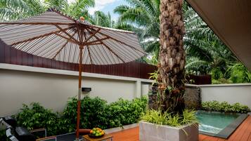 Una terrassa de fusta amb piscina, gandules, una taula plena de fruita i un gran parasol.