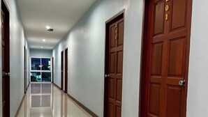 A long, well-lit hallway with multiple wooden doors, each marked with a number.