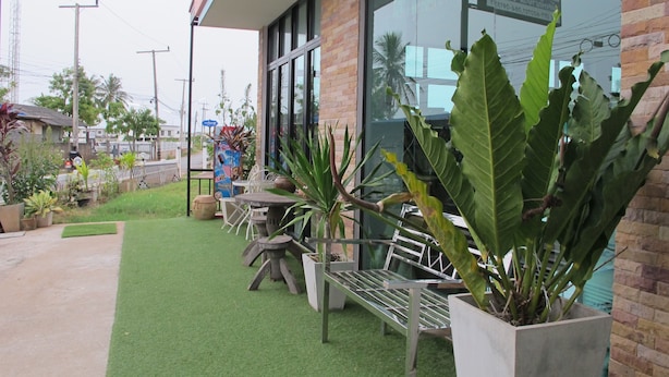 An outdoor seating area with a brick building, green artificial turf, and potted plants.