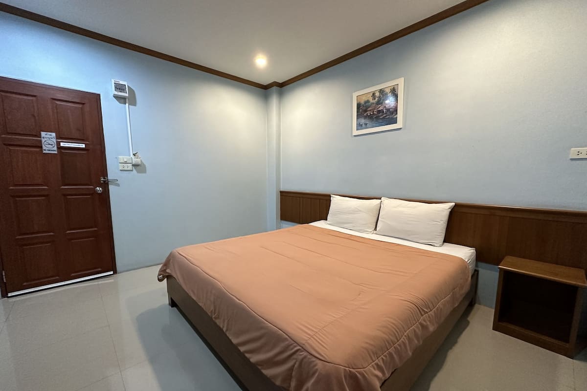 A bedroom with a bed, a nightstand, a door, and a wall-mounted air conditioner.