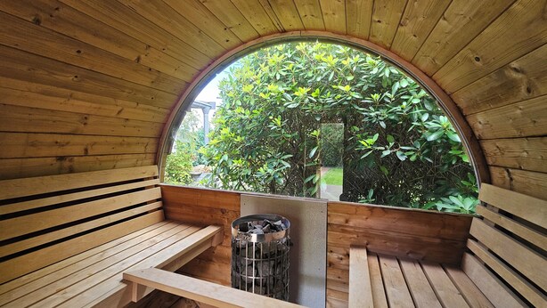 Un interior de madera con bancos y un ventanal con vistas a un jardín.