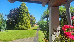 Un sendero en un jardín que lleva a un edificio con un porche de madera.