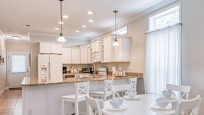 A modern kitchen with white cabinetry, granite countertops, and a breakfast bar.