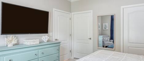 Een slaapkamer met een bed, een dressoir, een televisie en een deur.