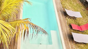 Una piscina con un pontile in legno e lettini da relax.