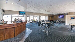 A spacious airport lounge with a wooden reception desk, multiple seating areas, and large windows providing views of the airport. - Merimbula Lakeview Hotel (Merimbula)