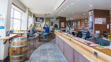 A restaurant interior with wooden bar stools, a counter with a menu, and a large window.