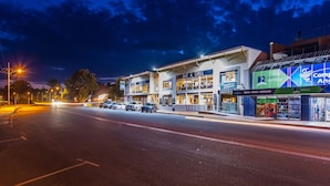 A street view at night with a hotel, bar & grill, and a camping world store. - Merimbula Lakeview Hotel (Merimbula)