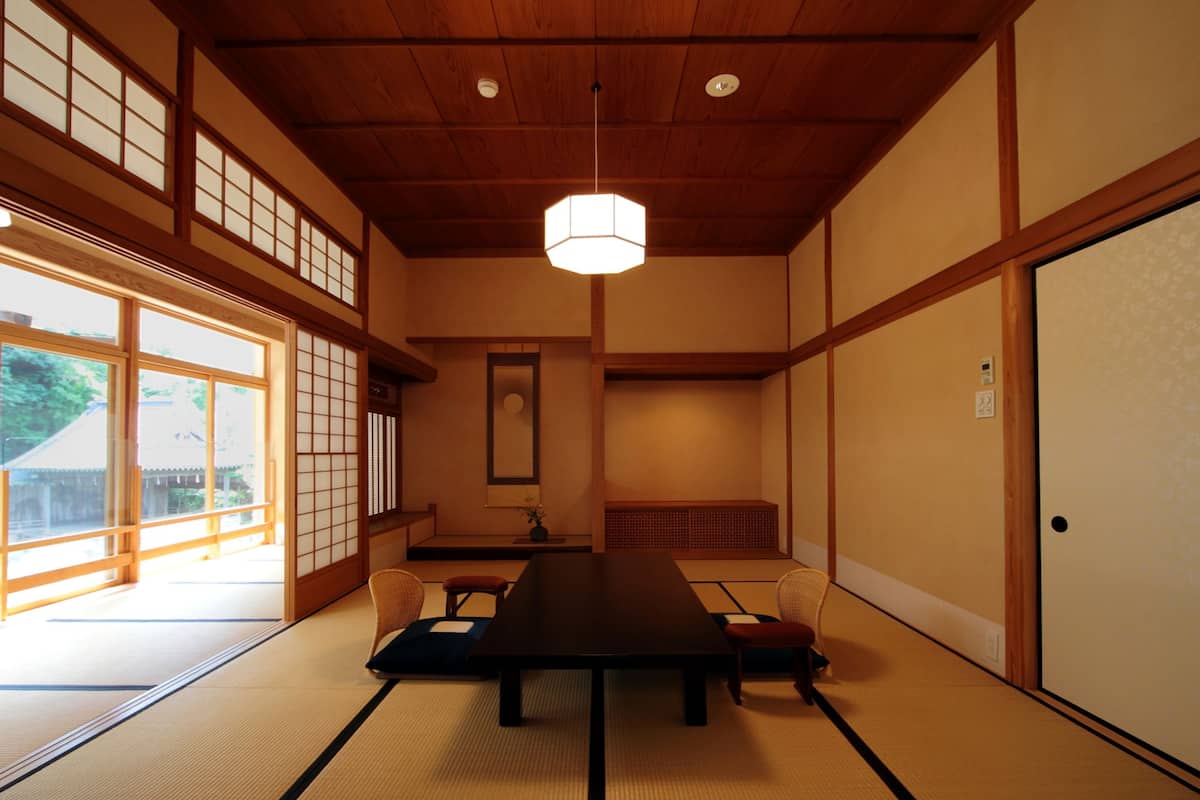 A traditional Japanese room with tatami flooring, a low table, and sliding doors.