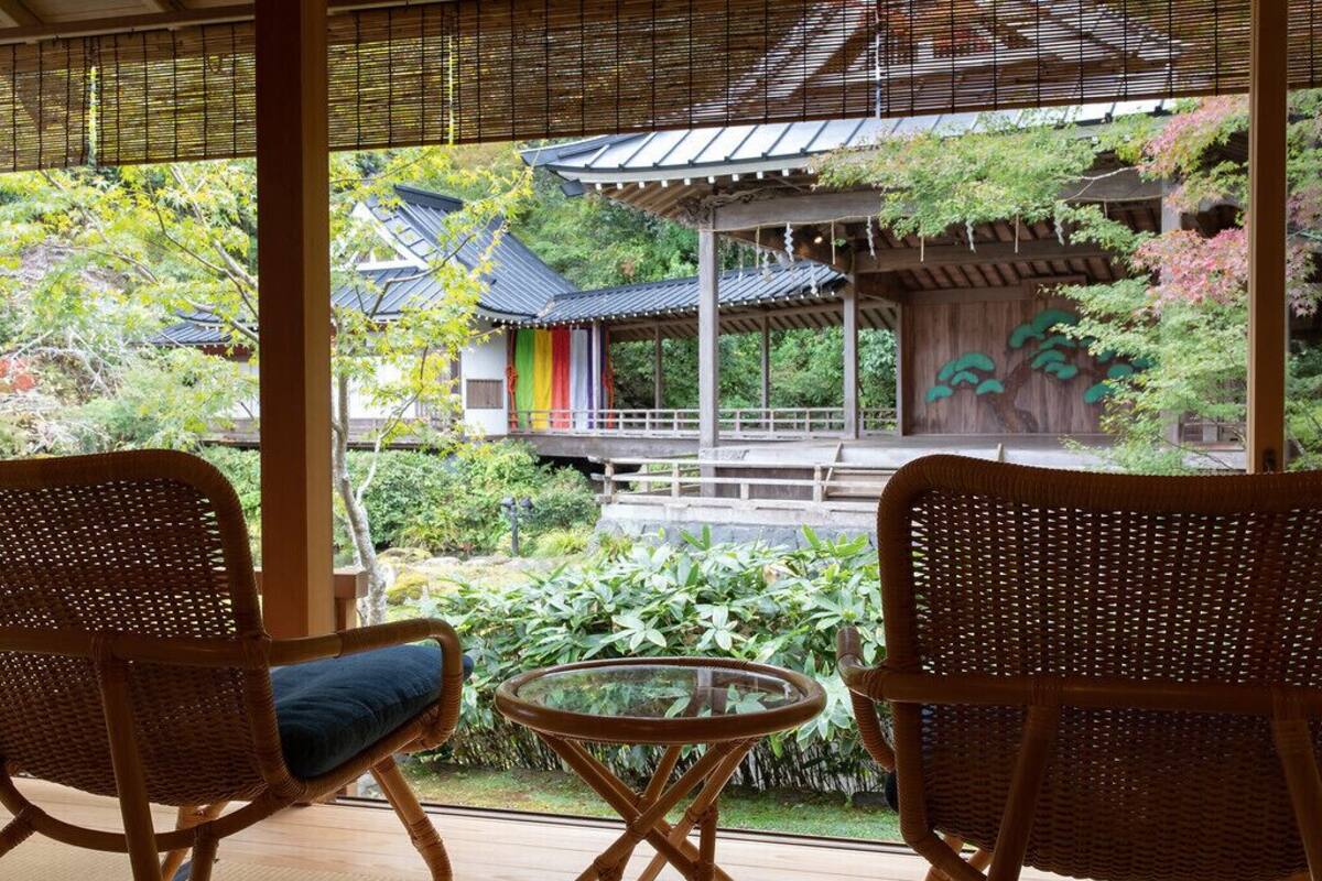 A traditional Japanese-style room with tatami flooring, a low wooden table, and two wicker chairs.