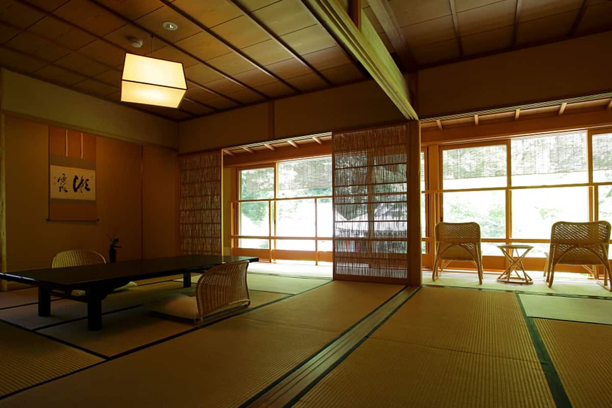 A tatami mat room with a low table, chairs, and a sliding door.