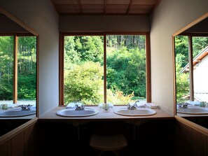 A bathroom with two sinks and a large window providing a view of a forest.