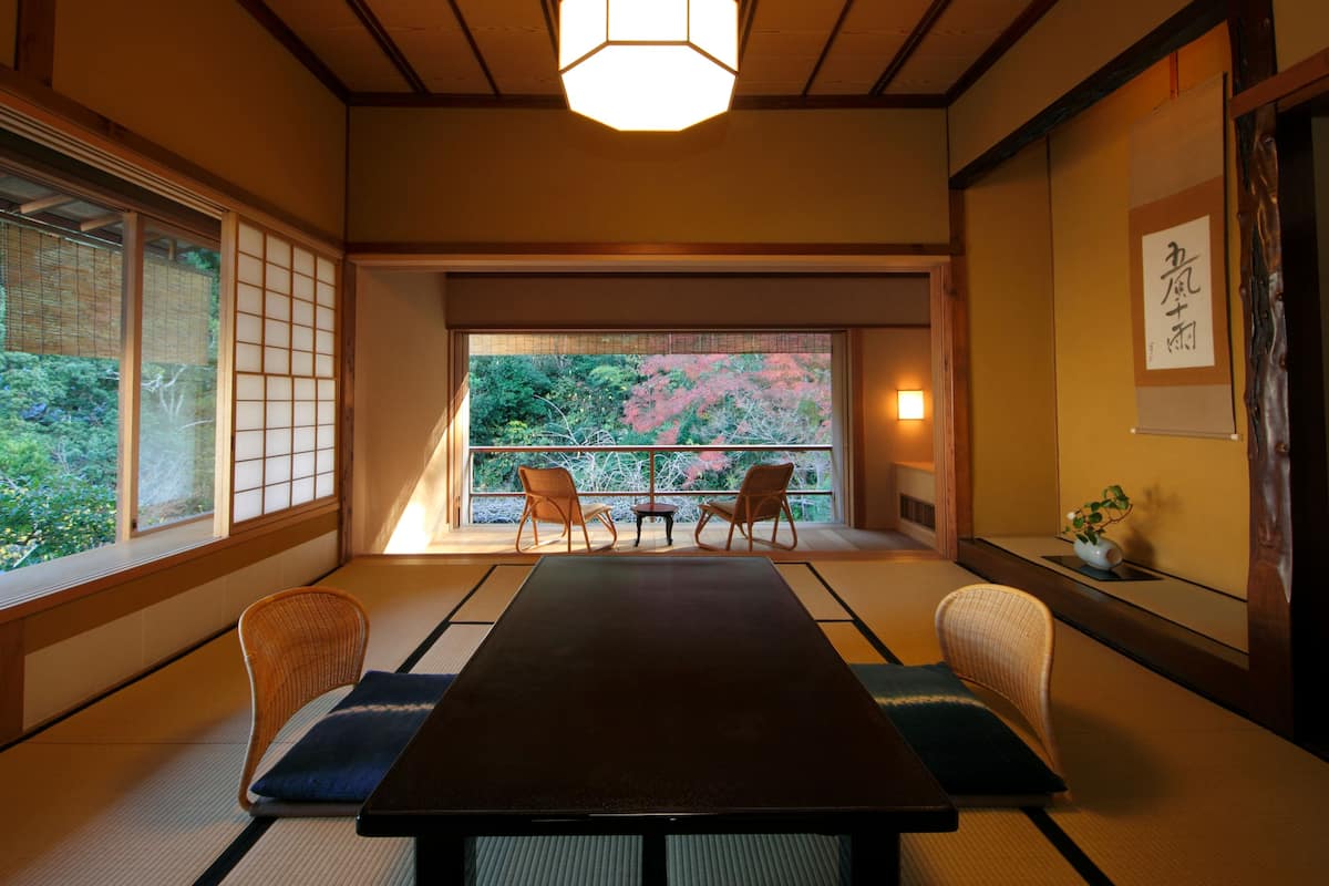 A traditional Japanese room with tatami flooring, a low table, and a view of cherry blossoms.