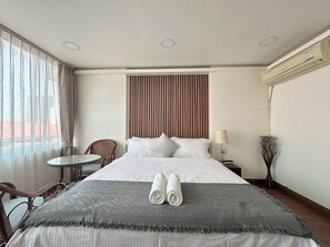 Una habitación de hotel con una cama, una silla, una mesita y una lámpara.