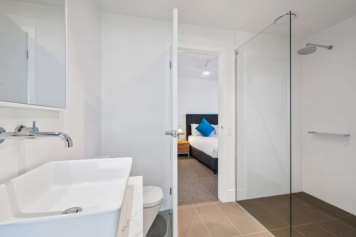 A modern bathroom with a large white bathtub, a separate toilet, and a glass-enclosed shower area.