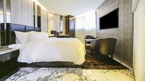 Une chambre d’hôtel moderne équipée d’un grand lit, d’un bureau, d’une chaise et d’un téléviseur.