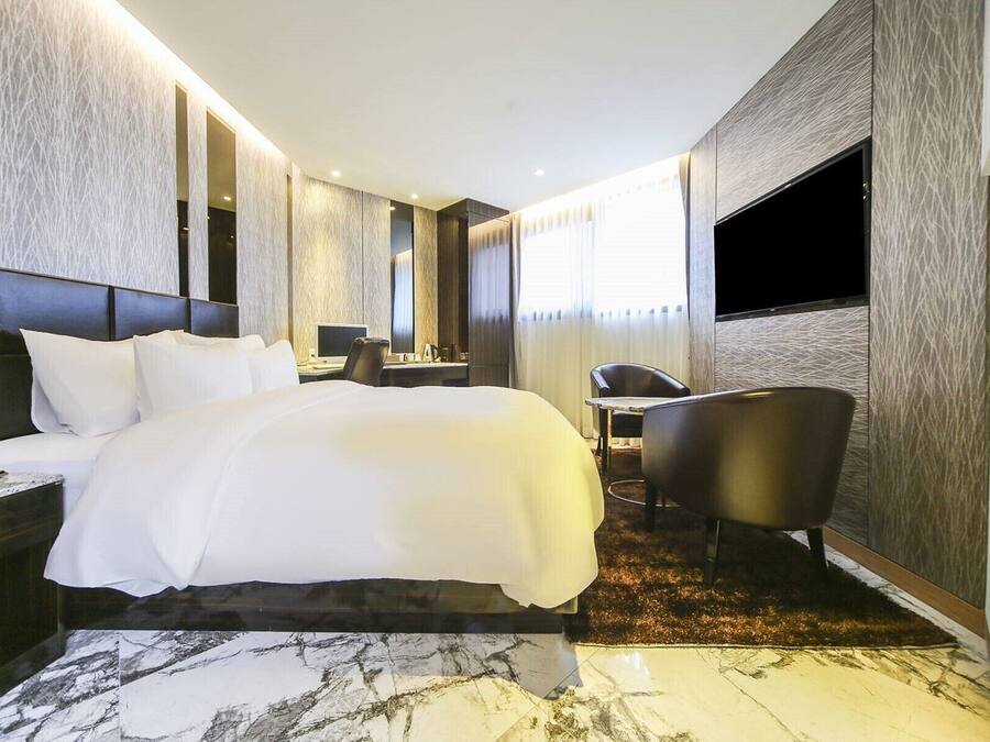 Una habitación de hotel moderna con una cama grande, un escritorio, una silla y un televisor.