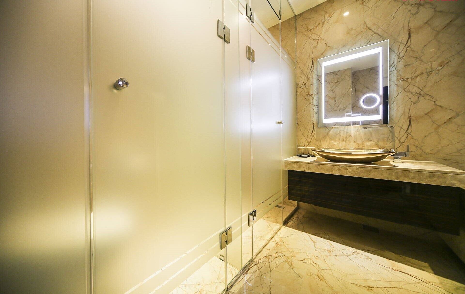 A modern bathroom with a marble floor, a vessel sink, and a mirror with integrated lighting.