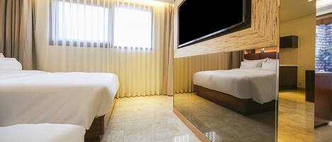 A hotel room with two beds, a large TV, and a view of the outdoors.