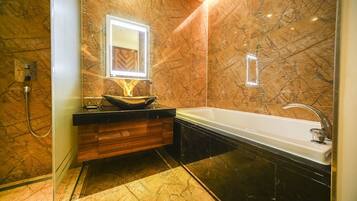 A modern bathroom with a marble floor, a wooden vanity, a large bathtub, and a mirror with a light.