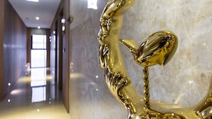 Un couloir agrémenté d’une sculpture dorée aux reflets chatoyants, de murs en marbre et d’un plafond au design moderne.