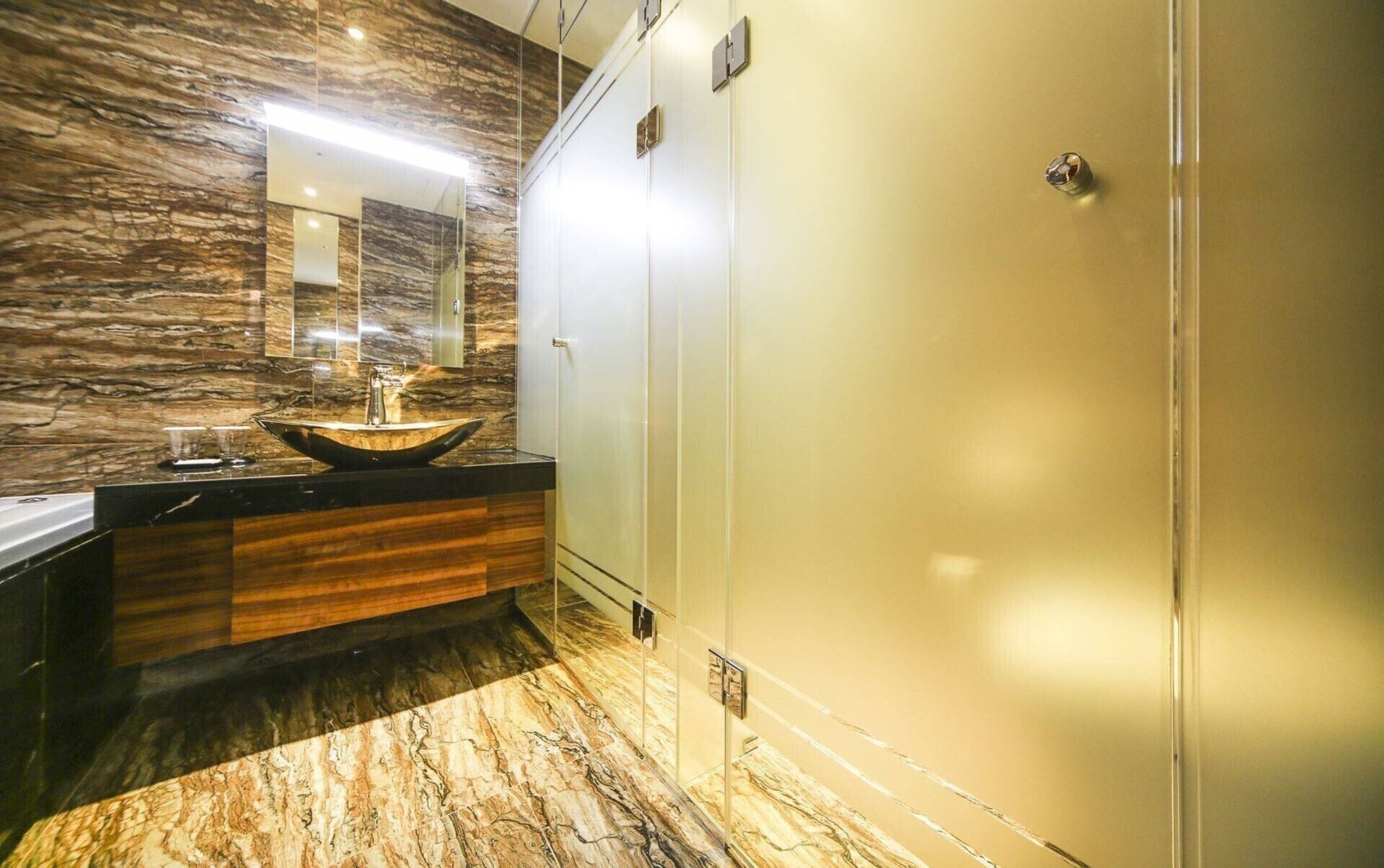 A bathroom with a marble floor, a vessel sink, and a mirror above it.