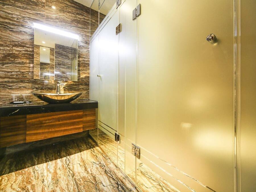 A bathroom with a marble floor, a vessel sink, and a mirror above it.