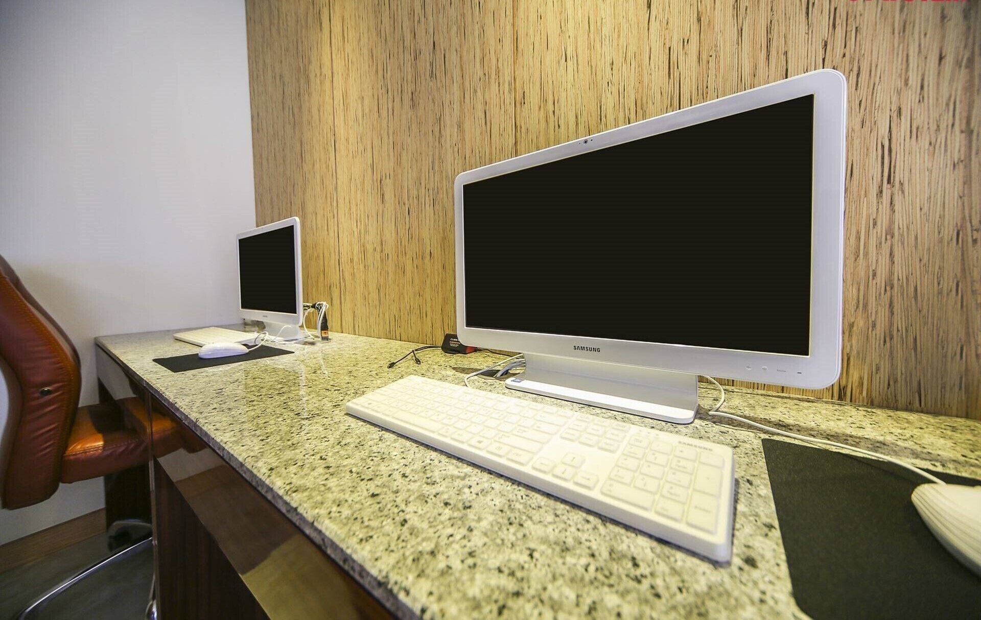 A desk with two monitors, a keyboard, and a chair.