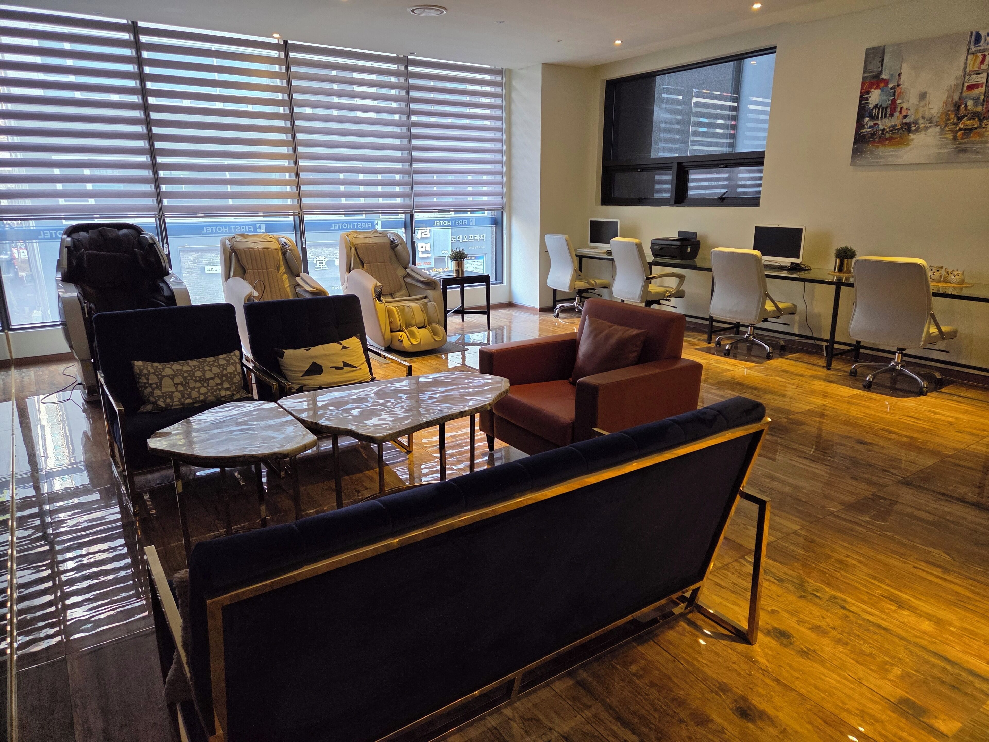 Une chambre d’hôtel moderne dotée d’une grande fenêtre, d’un canapé, d’une petite table et d’un bureau avec un ordinateur.